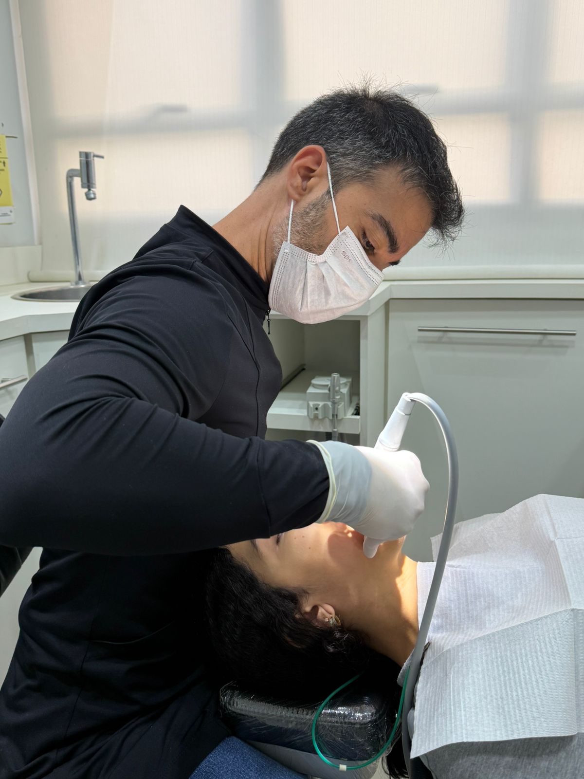 Close-up de um sorriso feminino harmônico após gengivoplastia, com contorno gengival simétrico e dentes proporcionais, gengiva rosada e saudável, fundo clínico desfocado em tons claros, iluminação suave e profissional, fotografia odontológica ultra-realista